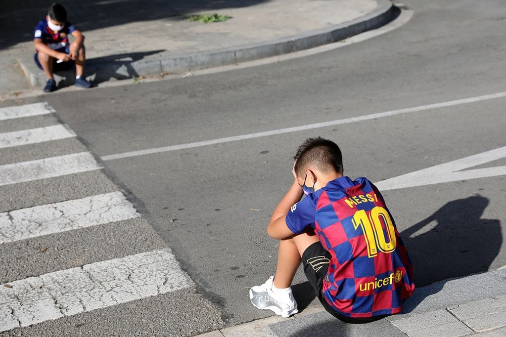 Boys sit on a street as they wait for FC Barcelona's squad to arrive for coronavirus disease (COVID-19) test, ahead of the resumption of training on August 31, in Barcelona, Spain August 30, 2020. REUTERS/Nacho Doce