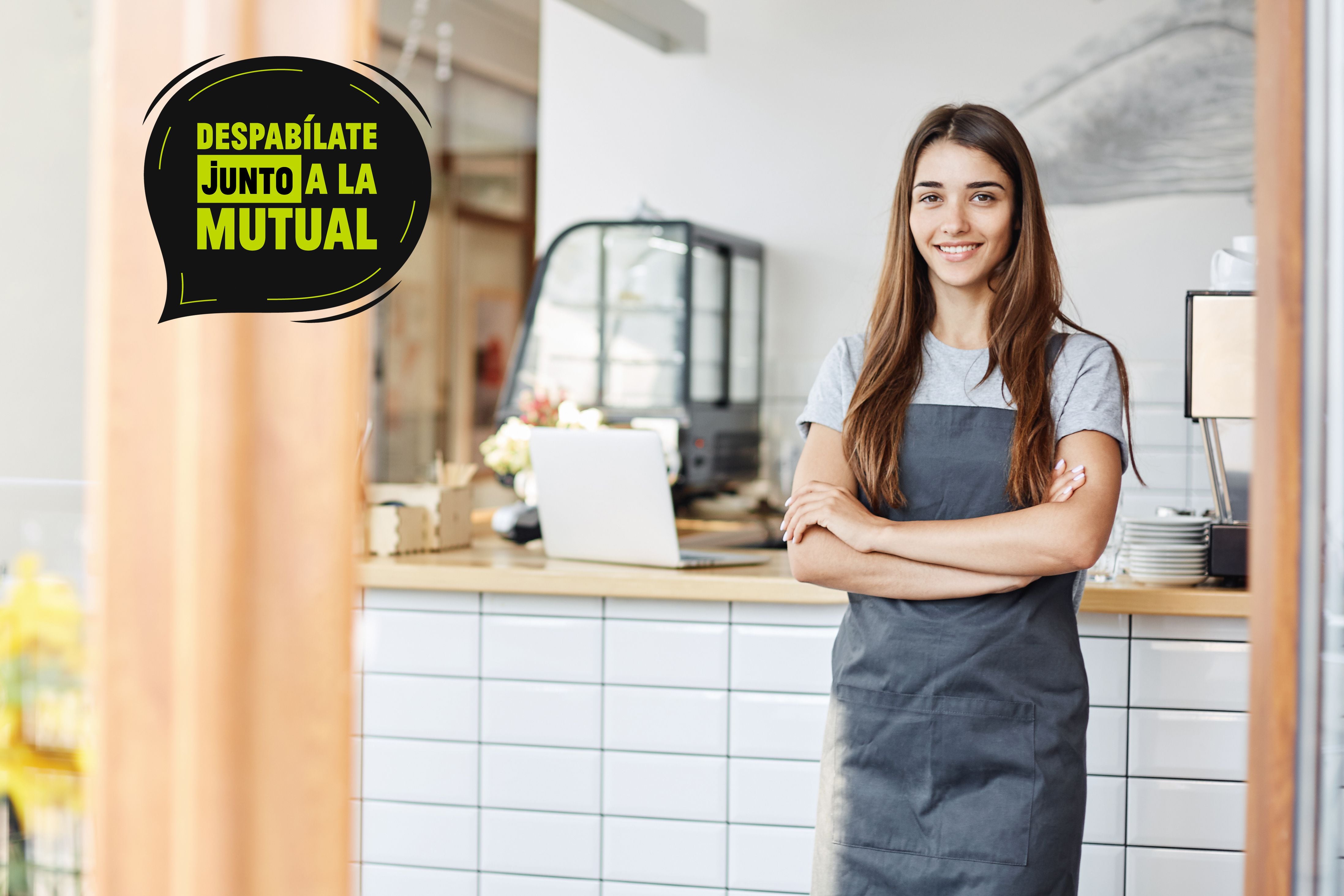 Young lady entrepreneur running a successful small cafe. Standing in front of coffee machine with arms crossed.