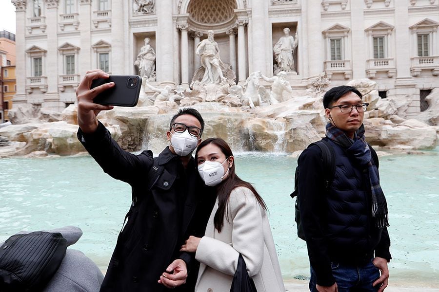 Tourists wearing protective masks take a selfie in front of ther Trevi's Fountain after two cases of coronavirus were confirmed in Italy