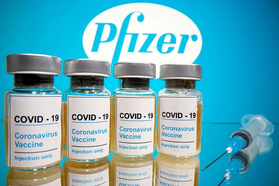 FILE PHOTO: FILE PHOTO: FILE PHOTO: Vials and medical syringe are seen in front of Pfizer logo in this illustration