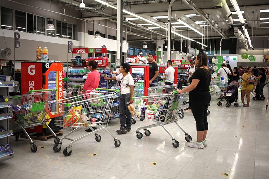 Personas se abastecen comprando en supermercados.