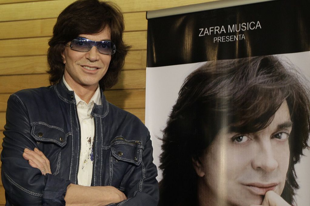 FILE - In this Nov. 4, 2009, file photo, Spanish singer Camilo Sesto poses next to a poster depicting himself during a news conference in Mexico City. Spanish singer and songwriter Camilo Sesto, a popular star in the 1970s and 1980s, has died of heart failure early on Sunday Sept. 8, 2019. He was 72. Sesto, whose real name was Camilo Blanes Cortes, sold more than 100 million records worldwide over his 40-year career. (AP Photo/Gregory Bull, file)