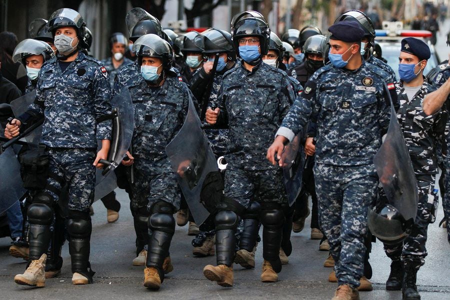 Lebanese police wear face masks as they walk together, during a protest against the collapsing Lebanese pound currency near Lebanon's Central Bank in Beirut