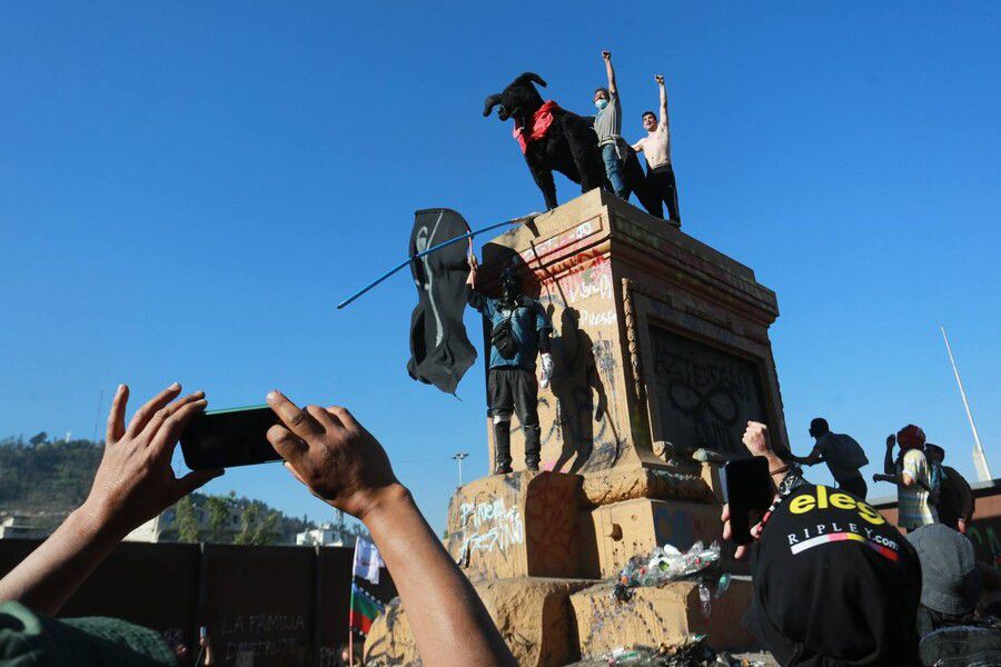 Manifestantes suben una enorme figura del "Negro Matapacos" al pedestal de Baquedano